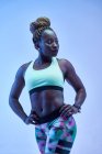 Мускулистая афроамериканка-спортсменка с потным телом на синем фоне показывает бицепсы — стоковое фото