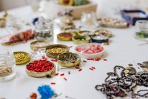 Side view of various decorative bugle beads in metal containers on wooden table — Stock Photo