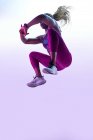 Anonymous African American female athlete with flying hair in sports clothes jumping with clasped hands during training — Stock Photo