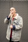 Auto fiducioso giovane transgender persona in giacca di jeans fumare sigaretta mentre guardando la fotocamera — Foto stock