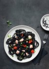 De acima mencionado espaguete de tinta preta com salmão em chapa cerâmica em fundo escuro — Fotografia de Stock