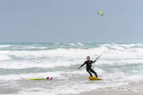 Athlète féminine active sur le kiteboard tenant la barre de contrôle tout en pratiquant le kitesurf et en regardant loin sur l'océan mousseux — Photo de stock
