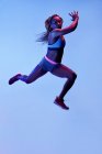 Бічний вид визначеного афроамериканського спортсмена, який стрибає з волоссям, дивлячись вперед під час тренування на кардіо — стокове фото