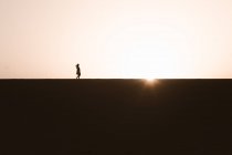 Anonimo turista donna che cammina contemplando il cielo luminoso con raggi di sole al crepuscolo — Foto stock