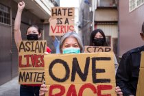 Attivisti etnici con le iscrizioni I Am Not A Virus e One Race sui cartelli durante il movimento Stop Asian Hate in città — Foto stock