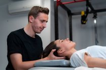 Вид збоку на неблагополучний чоловічий фізіотерапевт, що масажує шию жінки із закритими очима в лікарні — стокове фото