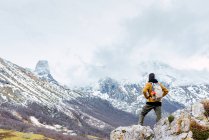Rückansicht des Wanderers mit Rucksack und warmer Kleidung, der auf felsigem Talrücken in Peaks of Europe steht und wegschaut — Stockfoto