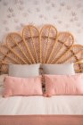 Comfortable cute natural vintage rattan headboard bed with ornamental cushions in a room — Stock Photo