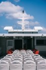 Палуба круїзного човна з порожніми білими стільцями в ряд під чистим небом з хмарами — стокове фото