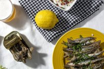 From above of traditional Spanish fried boquerones served on plates with lemons and bowl of white gazpacho soup placed on table with glass of beer in restaurant — Foto stock