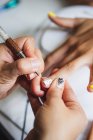 From above of crop unrecognizable manicurist doing nail art for female client in beauty salon in daylight — Stock Photo