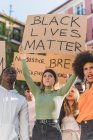 Crowd of multiracial people with Black Lives Matter poster protesting together on city street against racial discrimination — Foto stock
