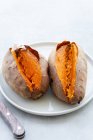 From above appetizing freshly baked sweet potatoes placed on white ceramic saucer on table — Stock Photo