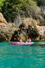 Viaggiatori vista laterale con pagaie galleggianti su acqua di mare turchese vicino alla riva rocciosa nella giornata di sole a Malaga Spagna — Foto stock
