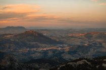 Vista panoramica di ampio terreno montuoso con piste coperte di verde sotto il cielo del tramonto a Siviglia Spagna — Foto stock