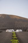 Modern white residential house located in middle of black lands against hills in haze — Foto stock