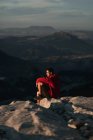 Side view of thoughtful male hiker in casual wear resting on rocky mountain summit and admiring scenic views over rough highlands in Seville Spain — Stock Photo