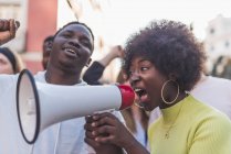 Вид сбоку на африканского американца в женском крик в мегафоне во время протеста против расовой дискриминации во время демонстрации черной жизни материи — стоковое фото