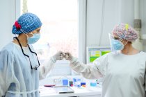 Doctors in uniforms greeting each other with high five at work in hospital — Stock Photo