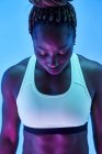 Joven deportista afroamericana con trenzas afro en moño y ojos cerrados sobre fondo azul - foto de stock