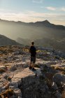 Indietro vista anonimo escursionista maschile in abbigliamento casual riposo sulla cima rocciosa montagna e ammirare viste panoramiche su altopiani grezzi a Siviglia Spagna — Foto stock
