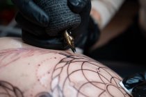 Жіночий татуювання з машинним малюнком татуювання на тілі невпізнаваного клієнта в салоні — стокове фото