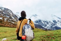 Back view of anonymous tourist with backpack standing on snowy lawn in valley of mountains in Peaks of Europe — Stock Photo