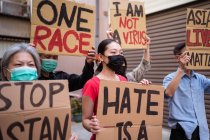 Activistas étnicos con inscripciones de I Am Not A Virus y One Race en pancartas durante el movimiento Stop Asian Hate en la ciudad - foto de stock