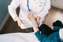 Hoher Winkel der Ernte anonymer Arzt in Uniform Wickelgaze um das Handgelenk des Patienten im Krankenhaus — Stockfoto