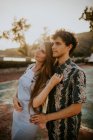Side view young loving couple wearing casual summer clothes hugging tenderly while standing on small village street on sunny day in Greece — Stock Photo