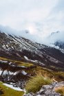 Campos verdes pintorescos con nieve en el valle de Picos de Europa bajo cielo nublado pesado en España - foto de stock