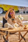 Bella ragazza asiatica che naviga sul telefono cellulare mentre si diverte seduto a tavola nell'area campeggio — Foto stock