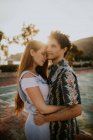 Ein junges verliebtes Paar in lässiger Sommerkleidung, das sich an einem sonnigen Tag in Griechenland zärtlich umarmt, während es auf einer kleinen Dorfstraße steht — Stockfoto