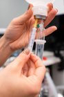 Ernte unkenntlich Tierarzt mit Injektor Füllung Drop-Counter mit Flüssigkeit gegen professionelle Geräte im Krankenhaus — Stockfoto