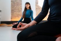 Ritaglia anonima femminile seduta a Padmasana e medita durante la lezione di yoga in studio — Foto stock