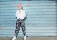 Selbstbewusster junger Homosexueller in trendiger Kleidung mit pinkfarbenen Haaren und Tätowierungen blickt in die Kamera — Stockfoto