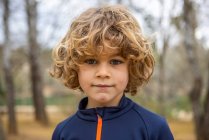 Charming child in sportswear clothes wear looking at camera on blurred background in daylight outdoors — Foto stock