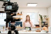 Молода жінка-блогер розмовляє зі смартфоном під час запису кулінарного відео і дивиться вниз по дому — стокове фото