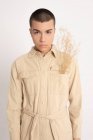 Андрогинная мужская модель в модной рубашке и с кучей сушеных растений, смотрящих на камеру на белом фоне в студии — стоковое фото