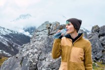 Женщина в теплой одежде, стоящая на высоких вершинах Европы и питьевой воде — стоковое фото