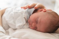 Cortar anônimo pai segurando bonito dormindo recém-nascido criança em casa no fundo borrado — Fotografia de Stock