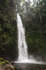 Vue imprenable sur une cascade puissante tombant d'une falaise rugueuse et raide dans un parc tropical — Photo de stock