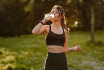 Junge Sportlerin trinkt Wasser in Trainingspause im Gegenlicht — Stockfoto