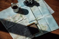 Top view of vintage photo camera and metal mug of coffee on route map during trip — Fotografia de Stock