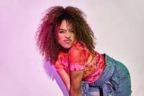 Fitte afroamerikanische Tänzerin in kurzen Hosen tanzt in die Kamera, während sie im Studio im Neonlicht steht — Stockfoto