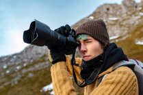 Vista lateral turista feminina com mochila usando câmera fotográfica enquanto fotografa incrível natureza de Peaks da Europa durante a viagem — Fotografia de Stock