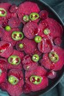Zusammensetzung von schmackhaften Rote-Bete-Scheiben auf Backform mit grünem Jalapeño-Paprika angeordnet und auf schwarzem Handtuch auf dem Küchentisch platziert — Stockfoto