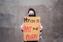 Femme ethnique en masque de protection debout avec Ma vie n'est pas votre carton porno affiche pendant la protection contre le harcèlement sexuel et les agressions — Photo de stock