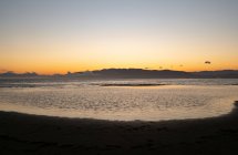 Мирный морской пейзаж на песчаном пляже возле спокойного моря на закате — стоковое фото
