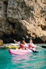 Side view travelers with paddles floating on turquoise seawater near the rocky shore on sunny day in Malaga Spain — Stock Photo
